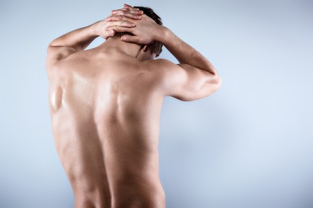 Studio shot of handsome young man with naked torso. Man suffering from neck acheの写真素材