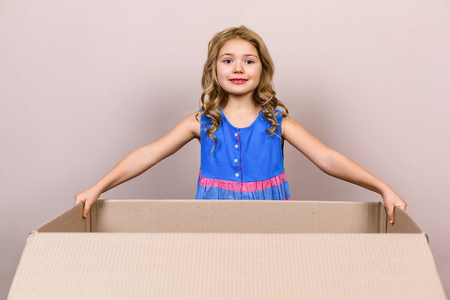 Playful childhood. Little girl having fun with cardboard box. Girl holding boxの写真素材