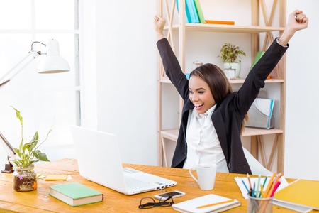 Beautiful young business woman in modern office with big window. Woman working with laptop and...
