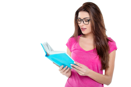Studio shot of beautiful young brunette woman. Pretty girl with glasses reading book. Isolated backgroundの写真素材