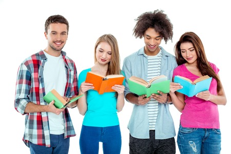 Studio shot of nice young multicultural friends. Beautiful people reading books. One boy looking at camera and smiling. Isolated backgroundの写真素材