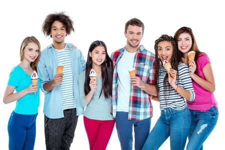 Studio shot of nice young multicultural friends. Beautiful people looking at camera, smiling and holding ice-creams. Isolated backgroundの写真素材