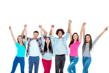 Studio shot of nice young multicultural friends. Beautiful people looking at camera, holding hands up and cheerfully smiling. Isolated backgroundの写真素材