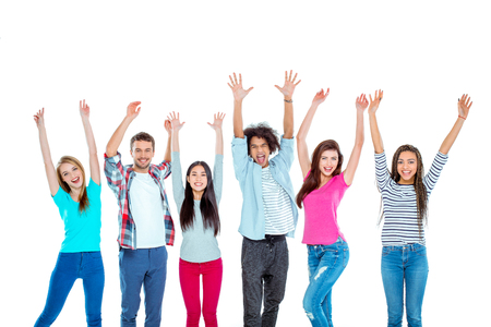 Studio shot of nice young multicultural friends. Beautiful people with hands up looking at camera and cheerfully smiling. Isolated backgroundの写真素材
