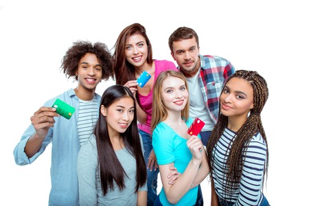 Studio shot of nice young multicultural friends. Beautiful people holding credit cards, looking at camera and smiling. Isolated backgroundの写真素材