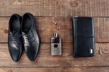 Top view photo of objects on wooden table. There are men's perfume, purse and shoesの写真素材