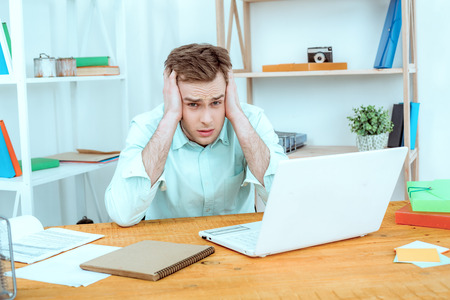 IT company. Young programmer working with laptop. Nice office interier. Professional coder is tired