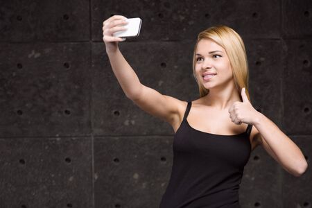 Portrait of stylish beautiful young blonde woman. Woman making selfie with mobile phoneの写真素材