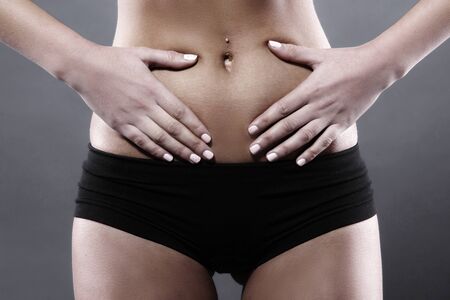 Body pain. Close up studio shot of woman. Woman suffering from underbelly painの写真素材