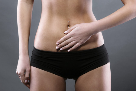 Body pain. Close up studio shot of woman. Woman suffering from underbelly painの写真素材