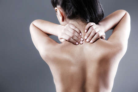 Body pain. Studio shot of beautiful young woman with dark brown hair. Woman suffering from neck acheの写真素材
