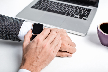 Close up photo of stylish handsome young man isolated on white background. Man with smart watch using laptopの写真素材