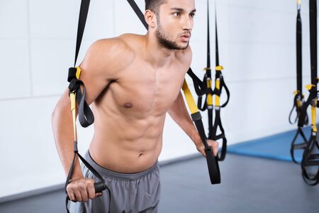 Young man training with TRXの写真素材
