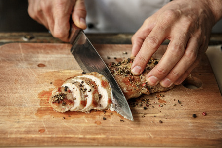 Mature male professional chef cooking meal indoors cutting meatの写真素材