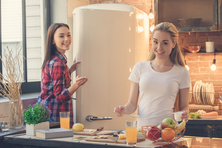 Young female friends cooking meal together at homeの写真素材