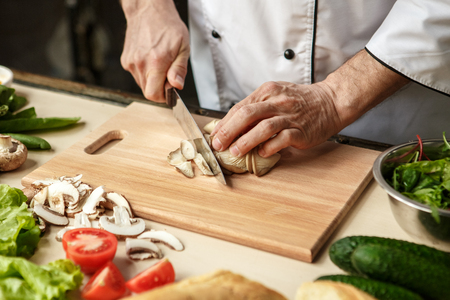 Mature man professional chef cooking meal indoorsの写真素材