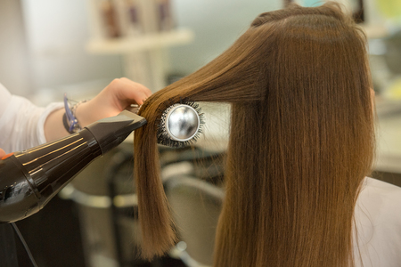 Young female sitting in hair salon hairdo styling hair dryの写真素材