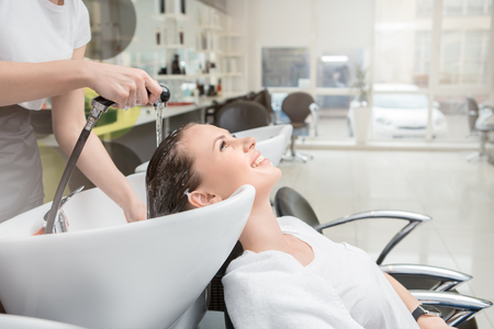Young female sitting in hair salon hairdo styling washing hairの写真素材