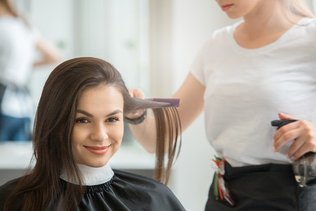Young female sitting in hair salon hairdo styling brushの写真素材