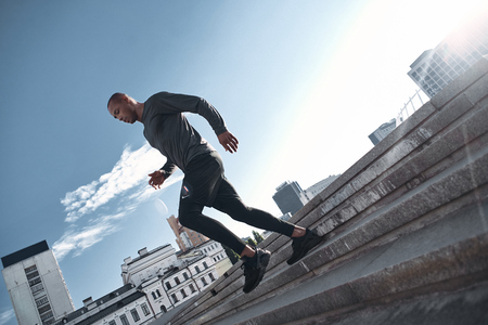 Urban sports. Latin american athlete running in city at morningの写真素材
