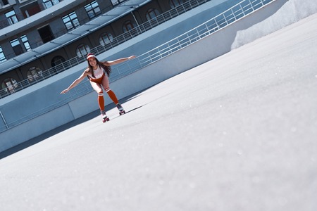 Beautiful girl is riding in rollers in skate park. She is doing that very active. She is happy.の写真素材