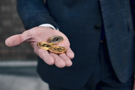Gold coins bitcoin stacked in the palms hands of a young woman on a dark background close-up. Crypto currency. Anonymousの写真素材