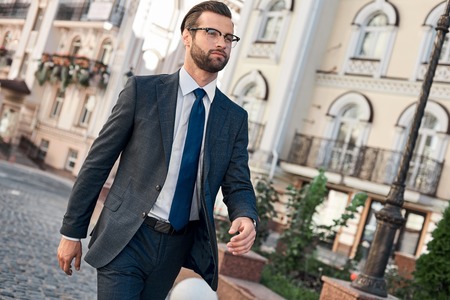 Confident and handsome. Full length of young man in full suit smiling while walking outdoorsの写真素材