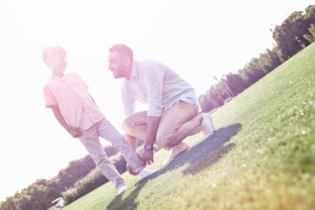 Family walk. Father fixing trousers of son smiling happyの写真素材