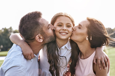 Togetherness, Family of three standing on grassy field hugging pの写真素材