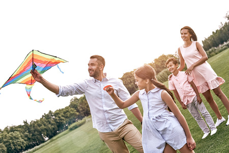 Weekend activities. Family with a kite walking on field in naturの写真素材