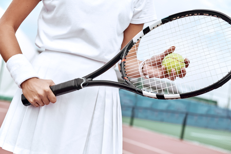 Close up of a young woman ready to hit a tennis ball, serving a ball during game.の写真素材