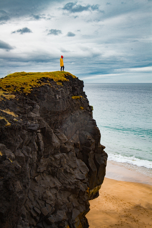 Icelandic landscape, person in yellow rain jacket. Amasing rock, Iceland.の写真素材