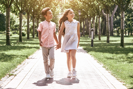 Friendship. Little boy and girl walking on the road in the parkの写真素材