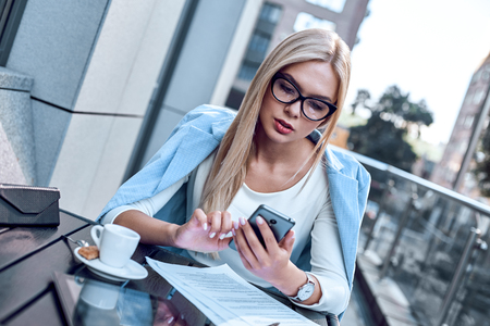 Young stylish woman chatting at smartphone in cafeの写真素材