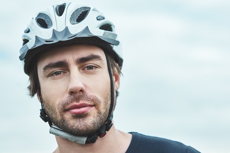 Attractive young man standing outdoors with protection helmet. Close upの写真素材