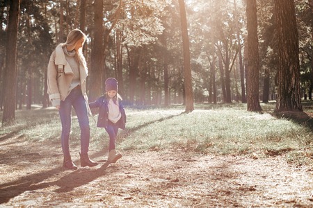 Nice walk with mom. A little curly girl is walking with her mother in forestの写真素材