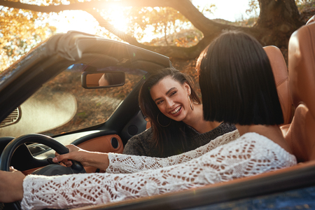 Side view of two happy women friends in cablioletの写真素材