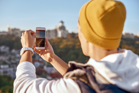 Young tourist blogger man is making selfie. Close-up, rear viewの写真素材