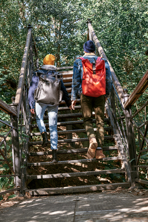 Happy romantic couple of tourists are ascending on steps. Rear viewの写真素材