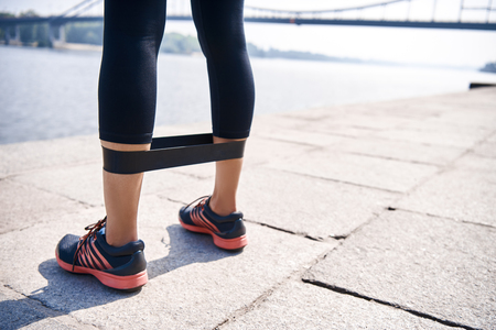 Young sporty woman doing exercises with rubber band outdoor.の写真素材