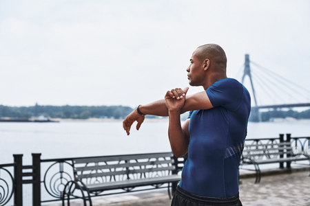 Close-up portrait of an african sportive man who is stretching handsの写真素材