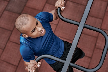 An african man is pulling up at open air gym. Close-up, top view