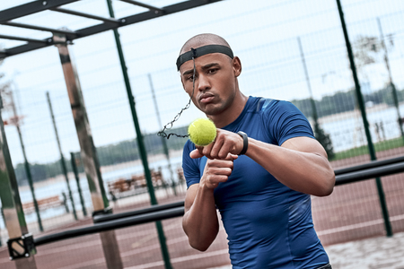 An african man is boxing with tennis ball at open air gymの写真素材