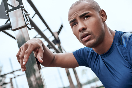 Young african man at the open air gym is resting after doing exercisesの写真素材