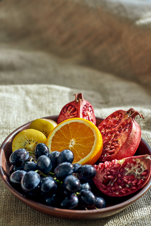 Overhead shot of a full plate of juicy, sliced fruits on wooden plateの写真素材