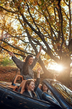 Portrait of three pretty young women in cabrioletの写真素材