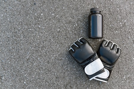 Sports boxing gloves with nutritional supplements at the asphalt backgroundの写真素材