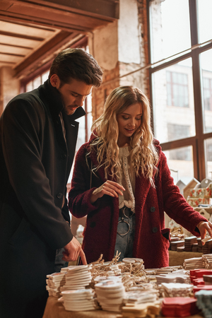 Happy young couple choosing handmade cristmas decorations at small street marketの写真素材