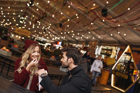 Young couple are eating french fries at the street food market.