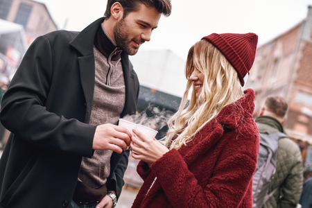 Young couple are drinking hot beverage, tea or coffee. Two cups togetherの写真素材